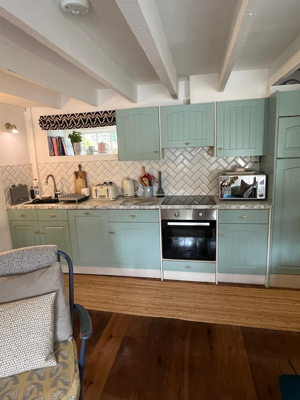 Sage green farmhouse kitchen with beams
