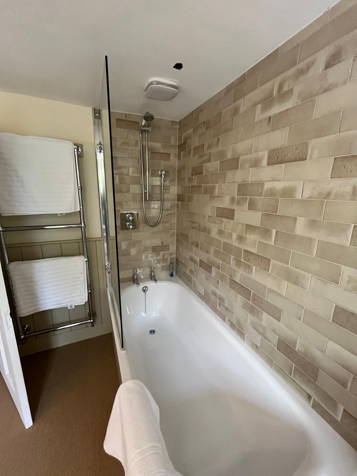 Shower room with warm brick tiles and fresh white towels