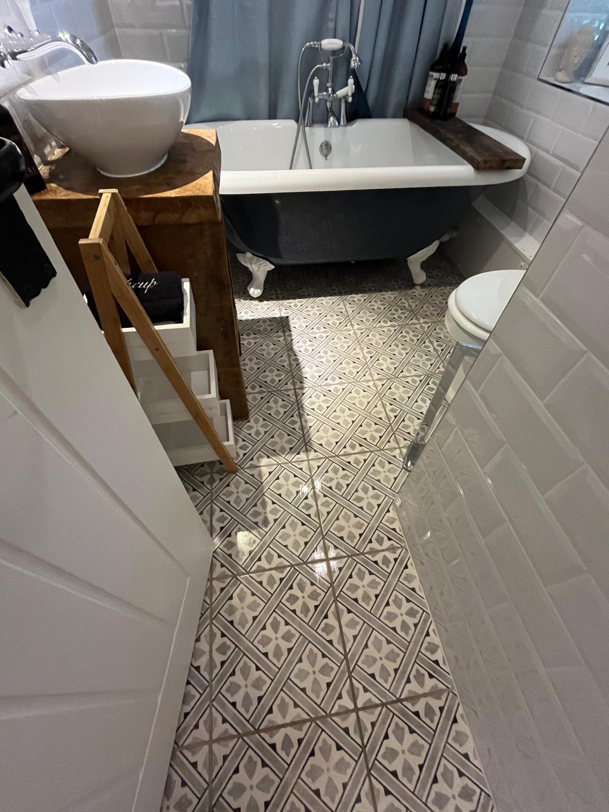 Bathroom with patterned floor tiles and a navy clawfoot bath