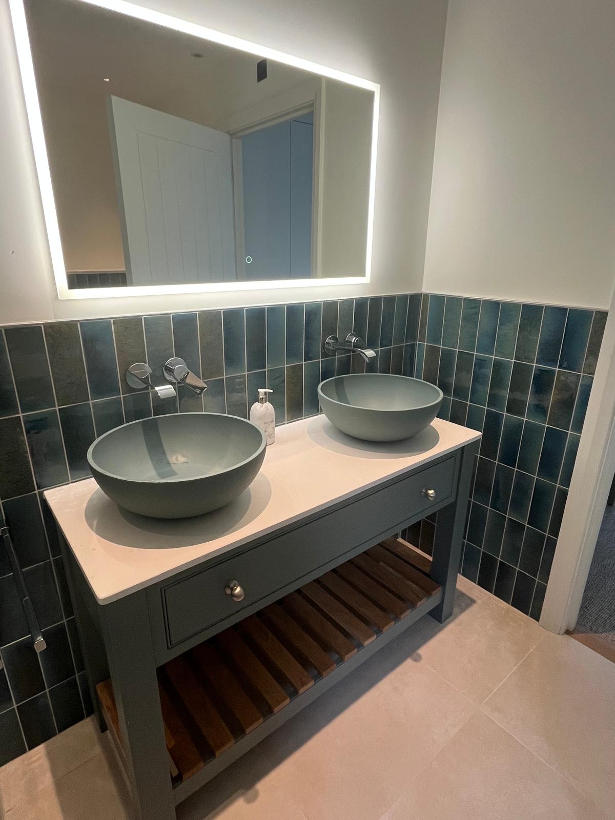 Twin bowl basins on a grey washstand with sea-green tiles