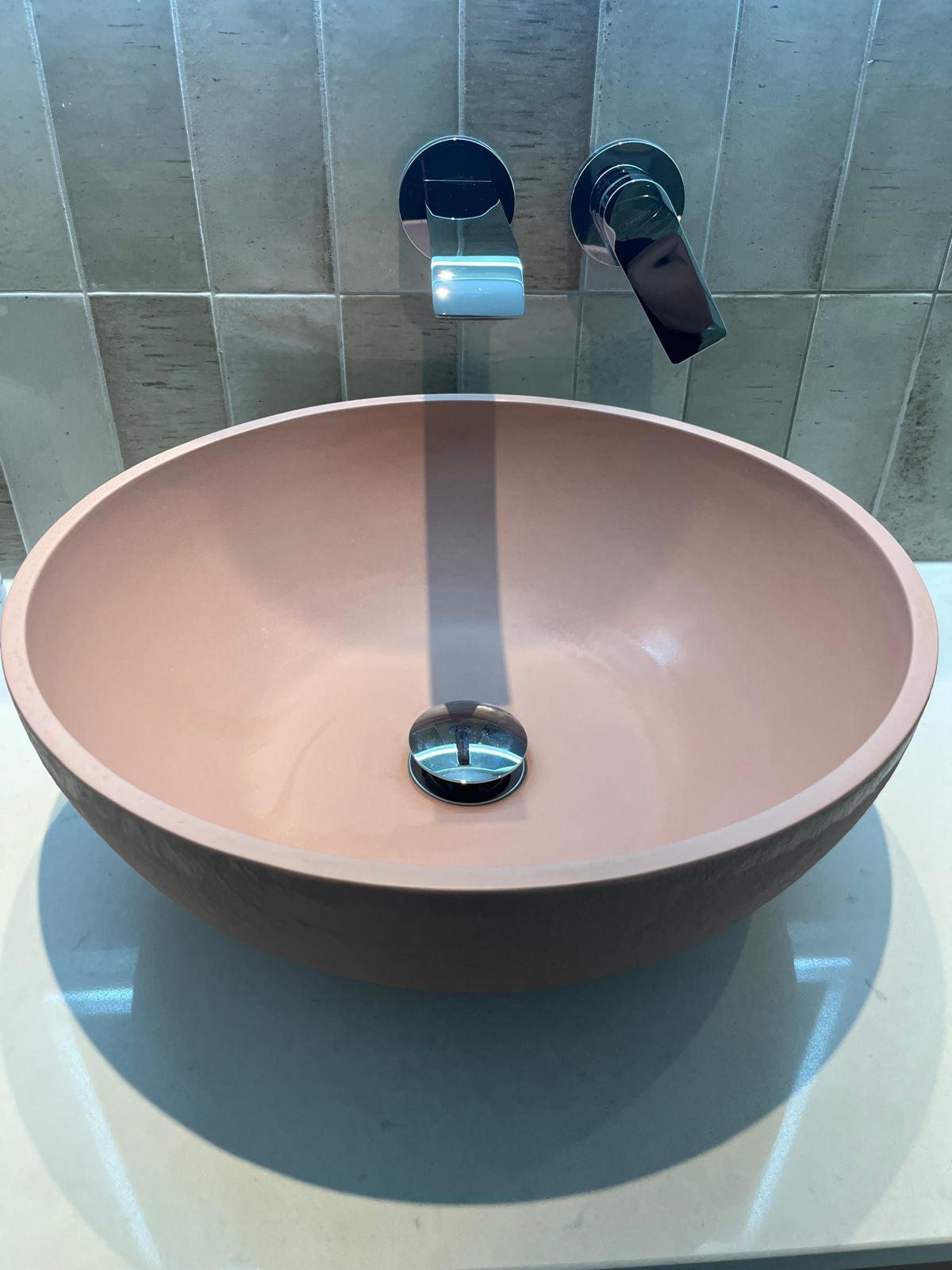 Blush stone basin with chrome wall-mounted taps