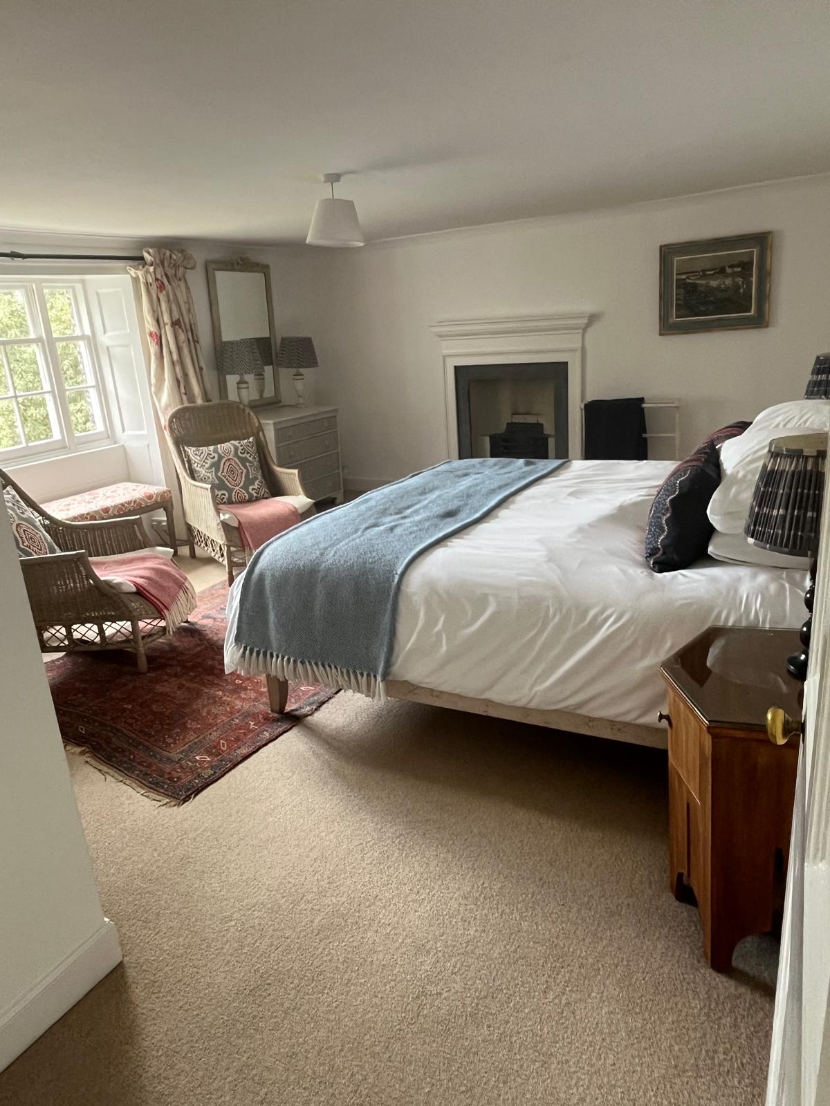Bedroom with fireplace and a made-up king bed